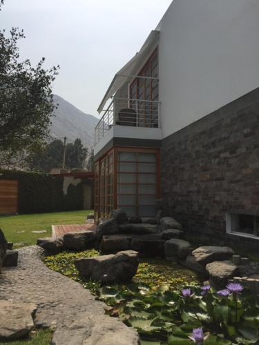 a building with a balcony and a garden with flowers at Zen Home & Garden House in Cieneguilla