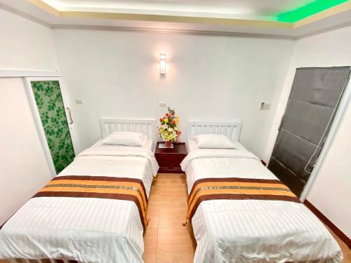 two beds in a room with white walls at ดอยตุง ฮันนาห์ โฮมสเตย์ in Ban Pa Kluai La Hu