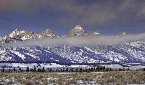 a snow covered mountain range with a cloud in front of it at Granite A in Jackson