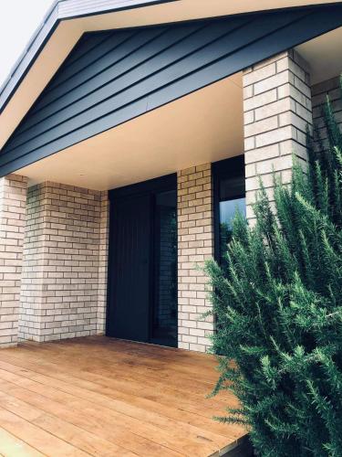 a house with a black door and a wooden deck at Mangawhai studio or a room in Guest's House in Mangawhai
