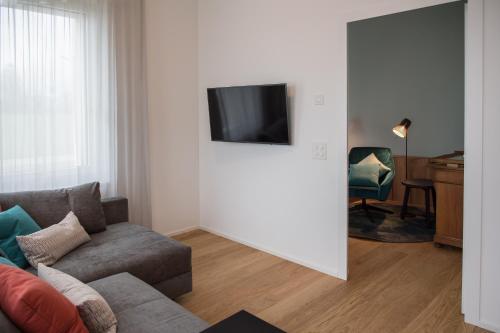 a living room with a couch and a tv on a wall at Aparthotel Luzern West in Alberswil