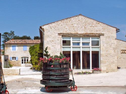a wheeled cart with flowers in front of a building at gites123soleil-glycine in Champagnolles