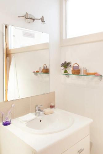 a white bathroom with a sink and a mirror at gites123soleil-glycine in Champagnolles