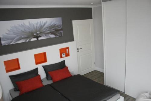 a bedroom with a black bed with red pillows at Haus-Amber-Mare-Strandtraeumer-9695 in Kühlungsborn