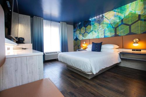 - une chambre avec un lit et une peinture murale dans l'établissement Hotel Denim, à Greensboro