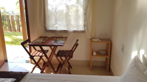 une table et deux chaises dans une pièce avec une fenêtre dans l'établissement Pousada Paraíso Mineiro, à Capitólio