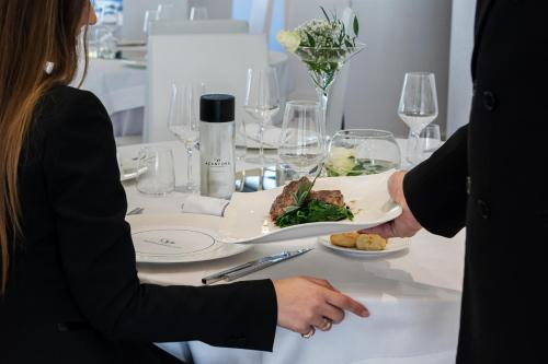 a man and woman sitting at a table with a plate of food at Mec Paestum Hotel in Paestum