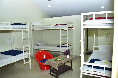 a room with bunk beds with a red chair and a table at Megha Resort , Hampi in Hampi