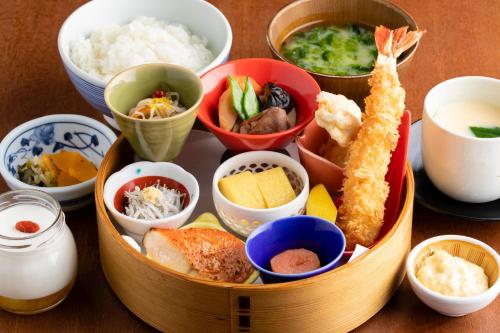 a wooden table topped with bowls of food at JR Kyushu Hotel Blossom Shinjuku in Tokyo