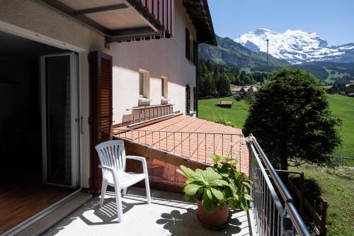 a white chair sitting on a porch of a house at Hotel Berghaus in Wengen