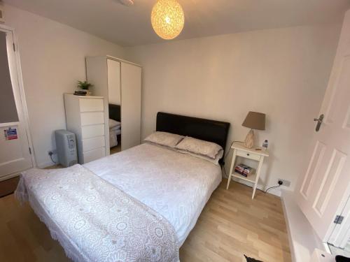a bedroom with a white bed and a night stand at The Rose Cottage Inn in Selmeston