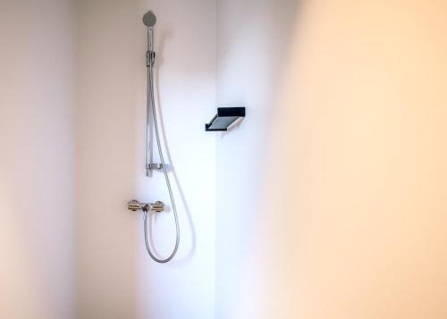 a shower in a white wall with a shower head at Apart! & Moment! in De Haan