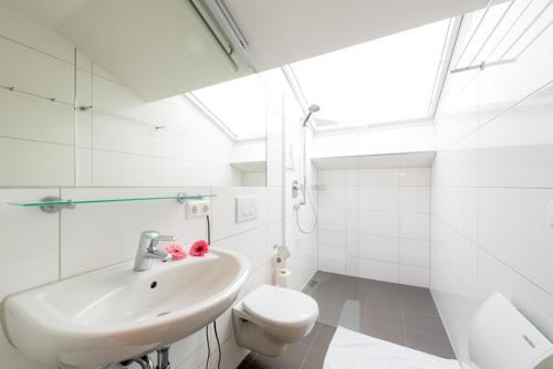 a white bathroom with a sink and a toilet at Ferienwohnungen "Am Kurpark" in Bad Aibling