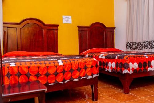 a bedroom with two beds with red and orange covers at Hotel Campo Real Plus Tamasopo in Tamasopo
