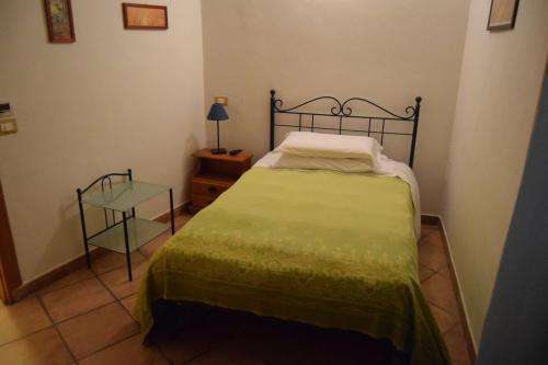 1 dormitorio con 1 cama con colcha verde y mesa en Teré Ceriana Affittacamere, en Ceriana