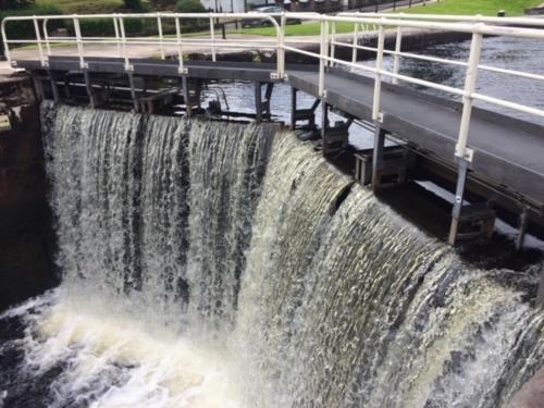 a large waterfall next to a road and a bridge at Lovat Loch Ness Apartment with private roof terrace in Fort Augustus