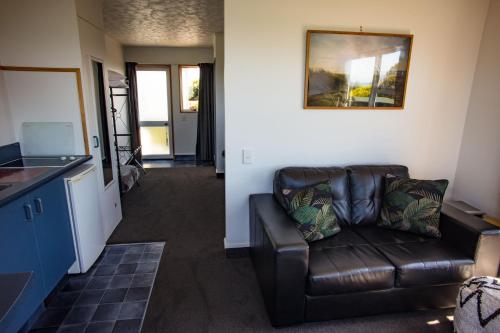 a living room with a brown leather couch in a room at Nugget View Kaka Point Motels in Kaka Point