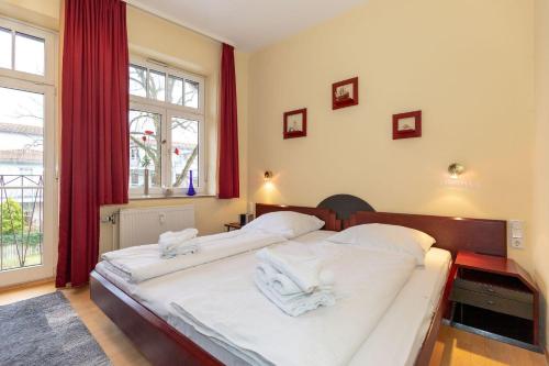 キュールングスボルンにあるResidenz-Ostseewind-Wohnung-16-280のベッドルーム1室(赤いカーテン付きの白いベッド2台付)