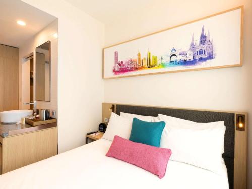 a bedroom with a bed with a painting on the wall at ibis Melbourne Central in Melbourne