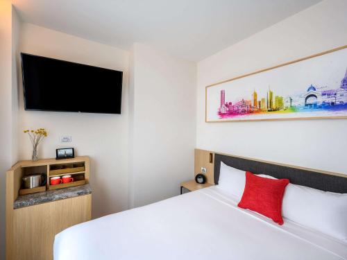 a bedroom with a white bed and a flat screen tv at ibis Melbourne Central in Melbourne