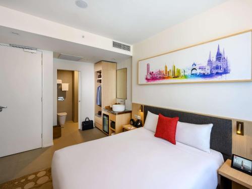 a bedroom with a large white bed with red pillows at ibis Melbourne Central in Melbourne