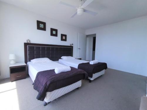 a bedroom with two beds and a ceiling fan at Condor Ocean View Apartments Surfers Paradise in Gold Coast