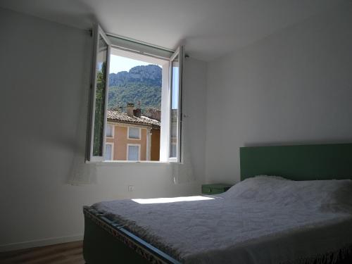 a bedroom with a bed and an open window at Appartement spacieux 6 personnes très lumineux in Buis-les-Baronnies