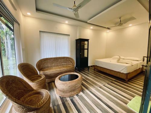 a bedroom with a bed and wicker chairs and a bed and a couch at Garggi Kumarakom Village Homestay in Kumarakom