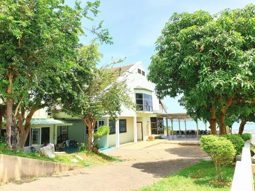 a white house with trees in front of it at โรงแรม ชาโตว์วิสต้า in Chon Buri