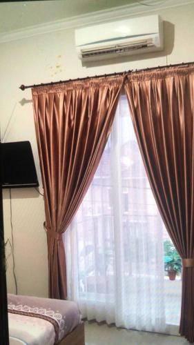 a bedroom with a window with curtains and a air conditioner at VILLA BAGUS KAYANA H2 DI BATU JAWA TIMUR in Batu