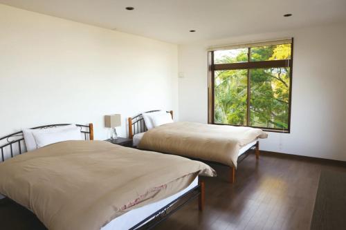 two beds in a room with a window at The Little Garden in Miyazaki