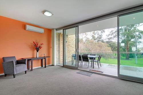 an open living room with glass doors and a table and chairs at Traralgon Serviced Apartments in Traralgon