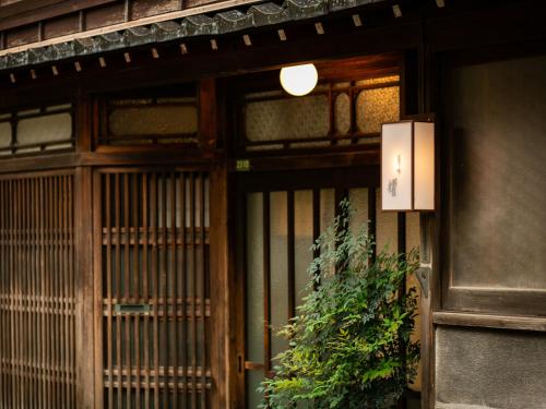 a door to a building with a plant in front of it at Maki No Oto Kanazawa in Kanazawa