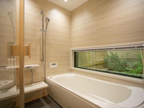 uma casa de banho com uma banheira e uma janela em Maki No Oto Kanazawa em Kanazawa