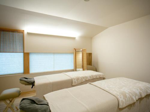 1 dormitorio con 2 camas, silla y ventana en Maki No Oto Kanazawa en Kanazawa