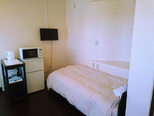 Habitación de hotel con cama y microondas en Eef Condominium Kumejima, en Kumejima