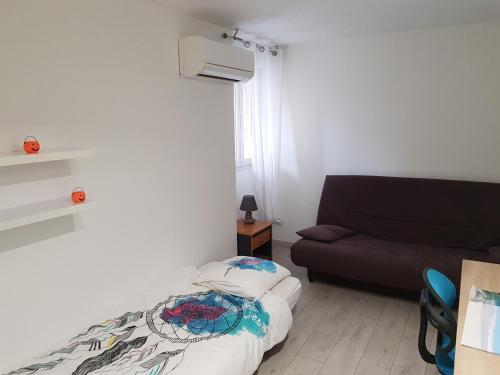 mały pokój z łóżkiem i kanapą w obiekcie Superbe appartement au calme proche de la plage w mieście Canet-en-Roussillon