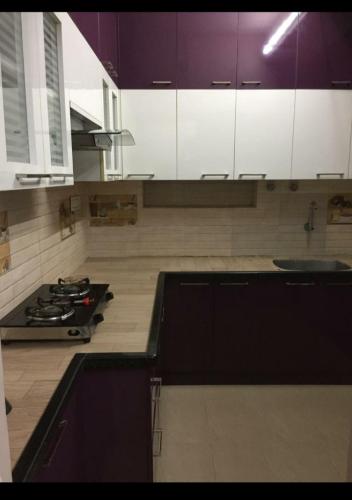 a kitchen with purple and white cabinets and a stove at Avvairam Service Apartment - C9 in Chennai