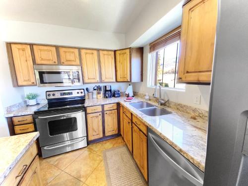 Una cocina con gabinetes de madera y electrodomésticos de acero inoxidable. en Ski Condo 1 mile to Deer Valley Gondola condo, en Heber City