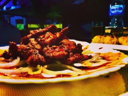 a plate of food with meat and onions on a table at Hotel the Narayani in Maruwā Ghāt