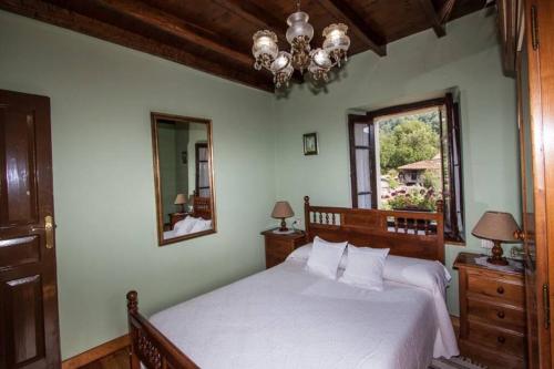 ein Schlafzimmer mit einem großen Bett und einem Spiegel in der Unterkunft Casa del Cuetu. Traditional village house in Asturias in Meré