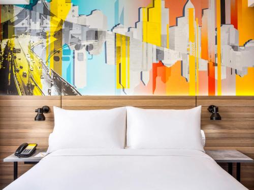 a bedroom with a white bed and a colorful painting at ibis Styles Bekasi Jatibening in Bekasi