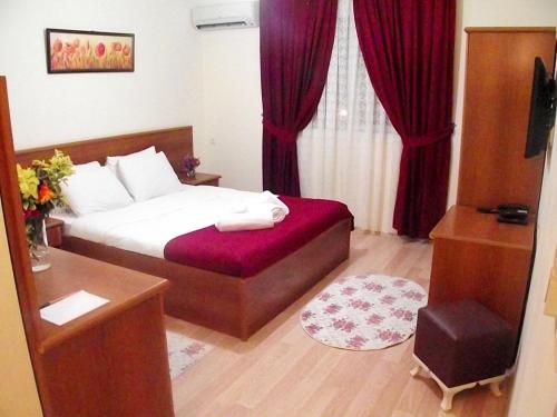 a hotel room with a bed with red curtains at Alize Resort Hotel in Yenifoça