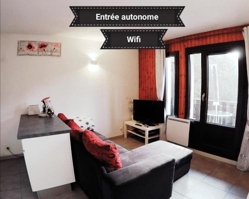 a living room with a couch and a sign that reads enter entrancealore at Studio plein sud, Wifi, Parking in Thollon