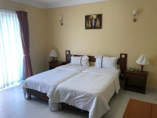 um quarto com uma cama grande e lençóis brancos em Don Bosco Hotel School em Sihanoukville