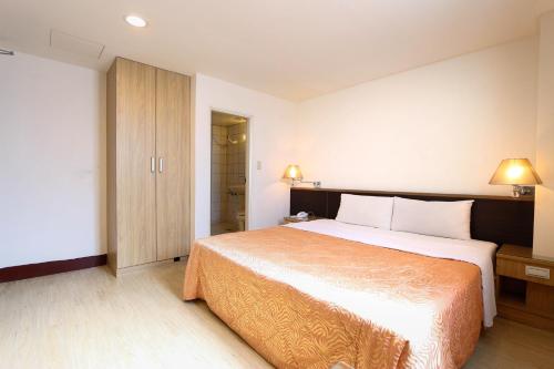 a hotel room with a large bed and a closet at D.Y. Hotel in Taichung