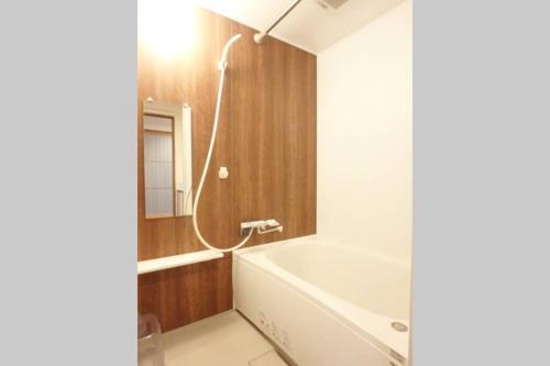 La salle de bains est pourvue d'une baignoire blanche et d'une douche. dans l'établissement Daiki Building 2, à Kyoto