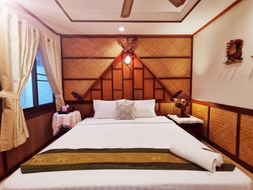 a bedroom with a large bed with a wooden headboard at TAVEE Guesthouse in Bangkok