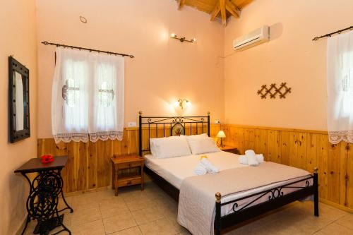a bedroom with a bed and a table and two windows at Artemis Vassilikos in Vasilikos