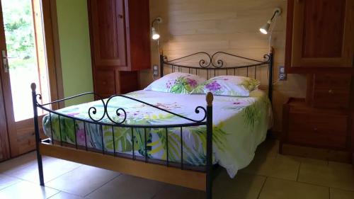 Un dormitorio con una cama de metal con flores. en Gîte des Conquettes en Salles-la-Source